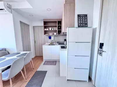 a white kitchen with a table and a refrigerator at Laguna Skypark 2 Bedroom scenic view in Laguna Phuket