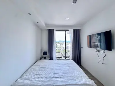 a bedroom with a bed and a tv and a window at Skypark New Building 4th floor Mountain View in Laguna Phuket