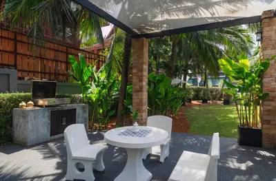 a patio with a table and chairs and a fireplace at Greenleaf Estate - Gated Villas with large shared pool, Nai harn beach in Rawai Beach