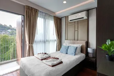 a bedroom with a bed with a large window at Ocean Horizon Residences - 2-BR, BangTao Beach in Ban Lum Fuang