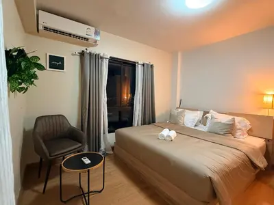 a bedroom with a bed and a chair and a window at 1BR Apartment Suite in the heart of Phuket Town in Ban Lo Long