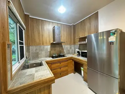 a kitchen with a stainless steel refrigerator and wooden cabinets at Kamala cozy home in Kamala Beach