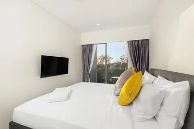 a bedroom with a white bed with a yellow pillow at Laguna LakeSide Residences by My Home Phuket in Bang Tao Beach