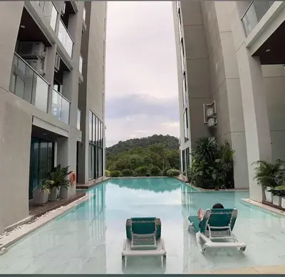 a man laying on two chairs in a swimming pool at patong see view condo in Patong Beach