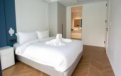 a large white bed in a room with a bathroom at Kora 222 3BR Condo with Pool Access in Phuket Town
