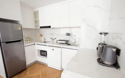 a kitchen with white cabinets and a stainless steel refrigerator at Kora 222 3BR Condo with Pool Access in Phuket Town