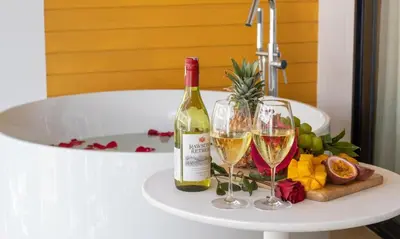 a bottle of wine and two glasses on a table next to a tub at One Bedroom Wyndham Naithon with Jacuzzi in Phuket Town