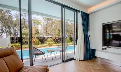 a living room with glass doors leading to a swimming pool at Kora 77 2BR Beachfront Condo with Sea View and Pool in Phuket Town