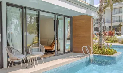 a house with a swimming pool and glass walls at Kora 77 2BR Beachfront Condo with Sea View and Pool in Phuket Town