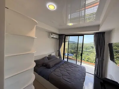 a bedroom with a bed and a large window at FAMILY HOMES Mai Khao Poolside Studio CB-845 Near Sirinat Park in Ban Mai Salae
