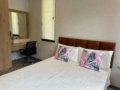 a bedroom with a bed with two pillows and a chair at Laguna villa with private pool in Ban Phru Champa