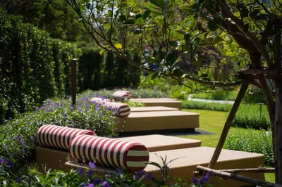 a row of benches in a garden with flowers at Lovely 2 Bdr Canvas BangTao in Laguna Phuket