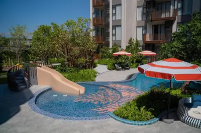 a swimming pool with a slide and an umbrella at Lovely 2 Bdr Canvas BangTao in Laguna Phuket