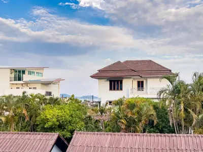 a white house with a red roof and trees at Rawai Lalaland Studio Apartments in Ban Saiyuan (1)