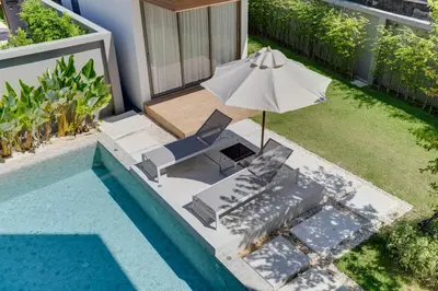 a swimming pool with an umbrella and a chair at New 4 bedroom villa 700 meters to Bang Tao Beach in Ban Thalat Choeng Thale