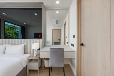 a bedroom with a bed and a desk with a chair at Suite Anafi 2BR Pool Gym Access Ozone in Laguna Phuket