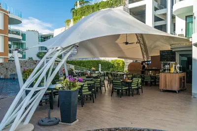 a patio with tables and chairs under a white umbrella at Sea view studio near Tri Trang & Merlin beach in Patong Beach