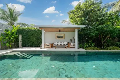 a swimming pool next to a villa with a table and a bench at Villa love with a garden in Phuket