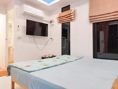 a bedroom with a bed with a tv on the wall at Suan Tha-Thong Homestay in Ban Bang Pla