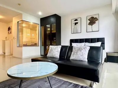 a living room with a black couch and a glass table at Chic condominimum in Karon Beach