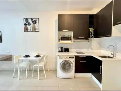 a kitchen with a washing machine and a table at Chic condominimum in Karon Beach