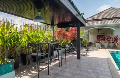 a patio with a table and chairs next to a pool at Greenleaf Estate - 3bedroom Villa with large shared pool, Nai harn beach in Rawai Beach