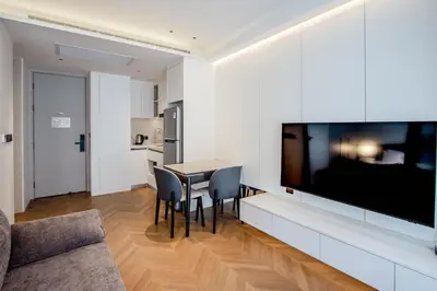 a living room with a dining room table and a large flat screen tv at KORA 243 One-Bedroom Residence in Phuket Town