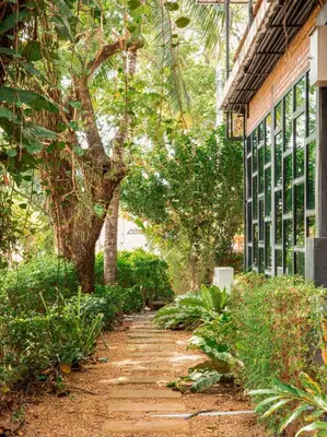 a garden path next to a building with trees at Tavana Residence in Ban Na Bon