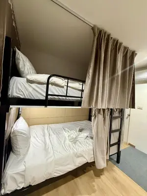 two bunk beds in a room with white sheets at Top Hotel Patong in Patong Beach