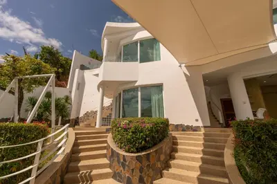 a white house with stairs and bushes at Villa Neptune Phuket - Luxury 6BR with Private Pool, Chalong in Ban Klang