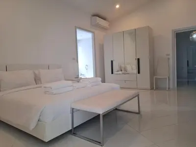 a white bedroom with a white bed and a table at Mango Villa in Ban Pa Khlok