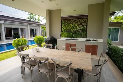 a wooden table and chairs on a patio at Beautiful Pool Villa in Pavilion and Tropical Oasis in Ban Pak Lak