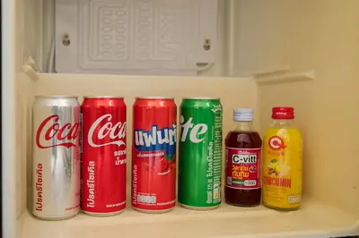 a shelf with cocacola cans and bottles of drinks at Chinoir Boutique Phuket Town in Phuket
