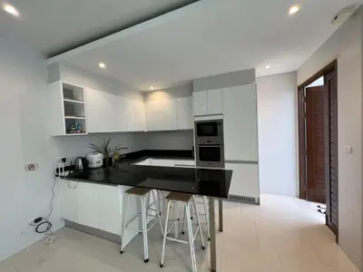 a kitchen with white cabinets and a black counter top at Pool Villa in Phuket 3rooms for family in Kamala Beach