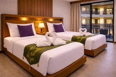 two beds in a hotel room with two swans towels at Aura Inn in Patong Beach