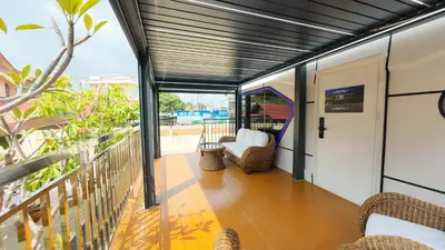 a room with a balcony with a door and chairs at Luxury Capsule Haus Phuket in Panwa Beach