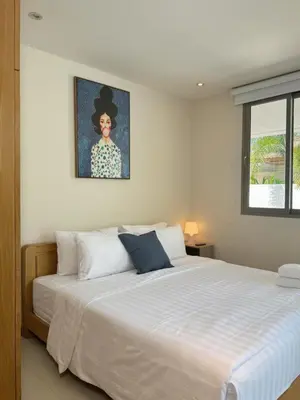 a bedroom with a large bed with a painting on the wall at Trichada Tropical Private Tropical 3BR Pool Villa in Laguna Phuket