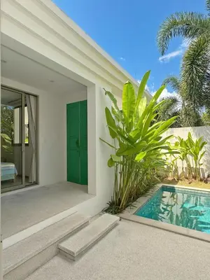 a villa with a swimming pool and a green door at Trichada Tropical Private Tropical 3BR Pool Villa in Laguna Phuket