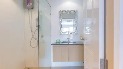 a bathroom with a sink and a shower with a mirror at Anda Beachside Hotel in Karon Beach