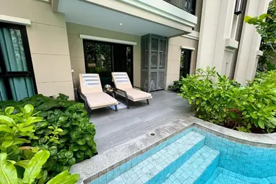 a patio with two chairs and a swimming pool at Title Legendary Pool Access Family suite D 107 in Ban Thalat Choeng Thale