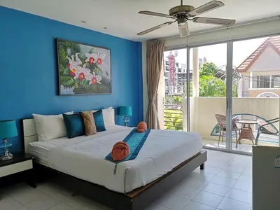 a bedroom with a large bed with a blue wall at Bed & Bath in Kata Beach