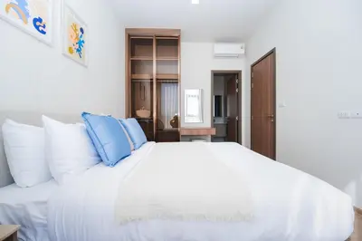a white bed with blue pillows in a bedroom at Casa tua, luxury 2bed - Canvas by Sansiri in Laguna Phuket
