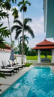 a swimming pool with lounge chairs and palm trees at Coastal Villa on Fairway 3 Bedroom in Laguna Phuket