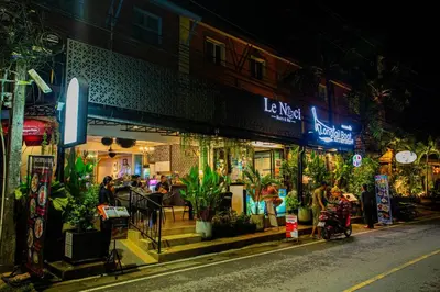 a street with people sitting outside a restaurant at night at Aonang room rent in Ban Khlong Haeng