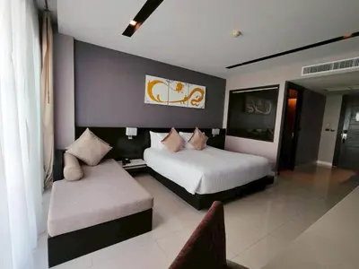 a hotel room with two beds and a couch at Beachfront 1 Deluxe BR Luxury Pool Patong Phuket in Patong Beach