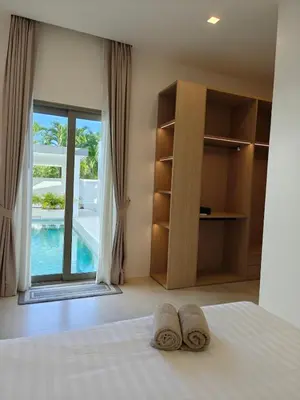 two slippers on a bed in a bedroom with a window at V-004 4 BR Unique Villa Baan Bua in Rawai Beach