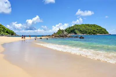 a beach with people walking on the sand and the ocean at 1 BR Apt Pool View - Babylon Sky M205 in Rawai Beach
