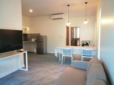 a living room with a table and a kitchen at TwinVillaSky in Ban Muang Mai