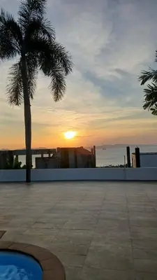 a sunset over a city with a palm tree on a building at Janjira sea view pool villa in Ban Ko Kwang