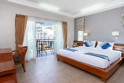 a bedroom with a large bed and a balcony at SawasdeeCiao Patong Guesthouse in Patong Beach